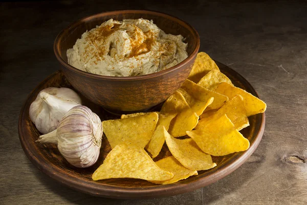 Hummus en un plato de barro y ajo —  Fotos de Stock