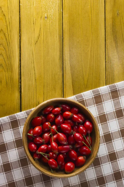 Ripe rosehips in wooden plate — Stock Photo, Image