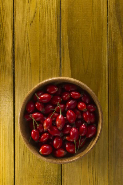 Ripe rosehips in wooden plate — Stock Photo, Image