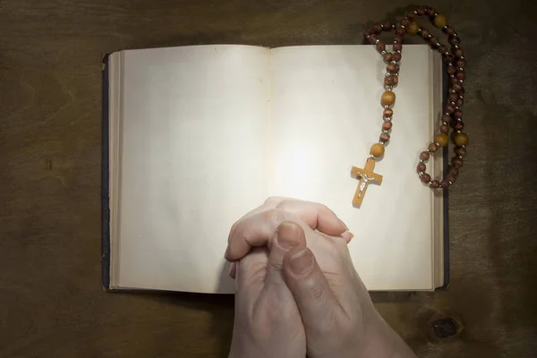 Hände mit Rosenkranz und einem alten Buch — Stockfoto