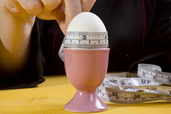 Egg in holder and hands with tape measure — Stock Photo, Image