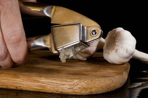 Garlic press and cloves of garlic — Stock Photo, Image