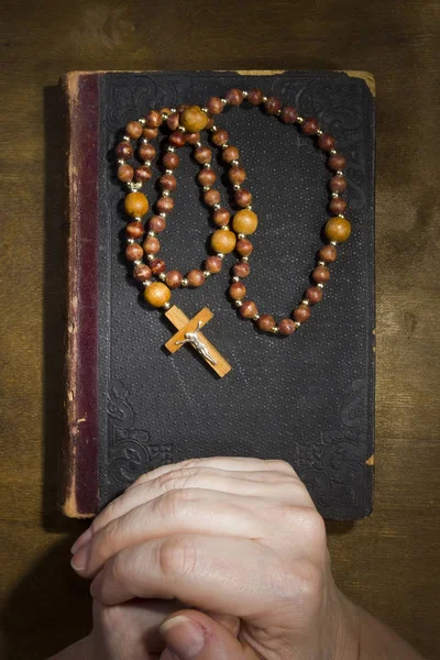 Mani con rosario e un vecchio libro — Foto Stock