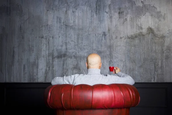 Łysy mężczyzna w czerwony fotel — Zdjęcie stockowe