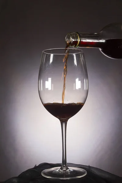 Vinho é derramado da garrafa no copo — Fotografia de Stock