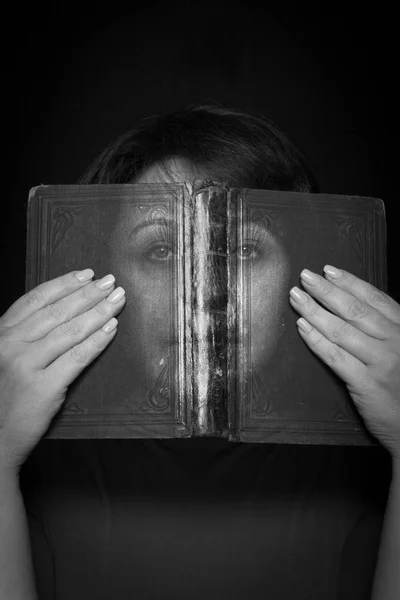 Una donna guarda attraverso un libro — Foto Stock