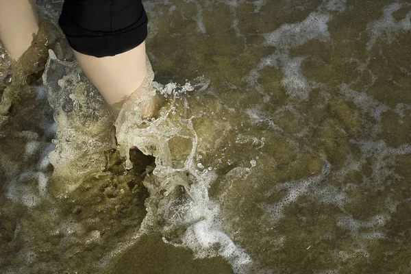 Морские волны умывают женские ноги — стоковое фото