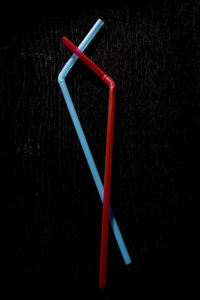 Straws for cocktails on a black wooden background