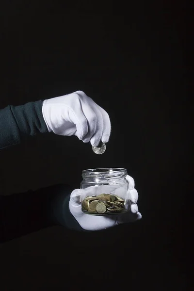 Hand throws a coin in a jar — Stock Photo, Image