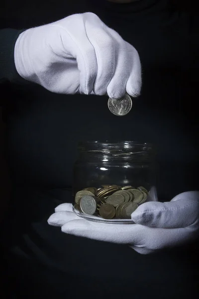 Hand throws a coin in a jar — Stock Photo, Image