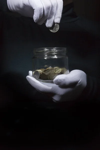 Рука бросает монету в банку — стоковое фото