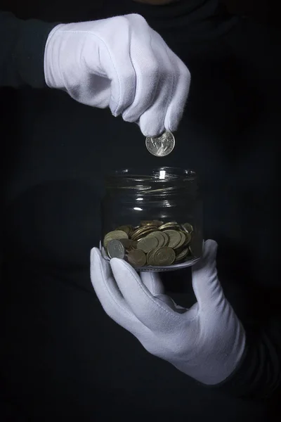 Hand throws a coin in a jar — Stock Photo, Image