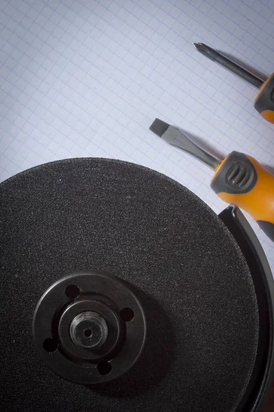 Angle grinder and screwdrivers on notebook — Stock Photo, Image