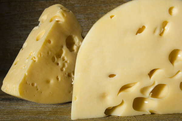 Pieces of cheese on old wooden background.