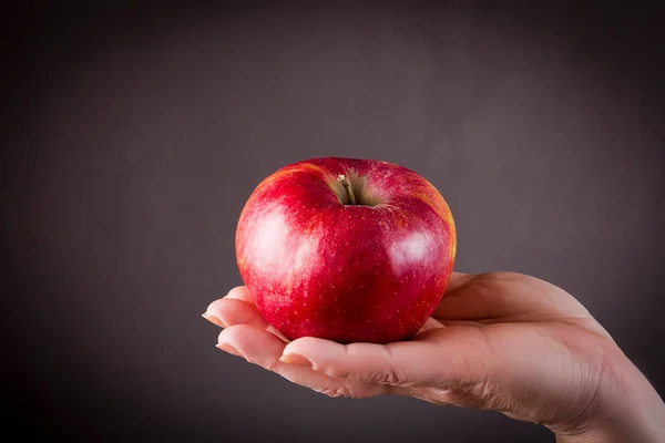 Weibliche Hand Hält Einen Apfel Auf Schwarzem Hintergrund — Stockfoto