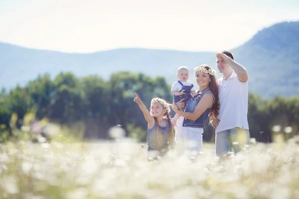 Familia feliz en un campo de margaritas florecientes — Foto de Stock