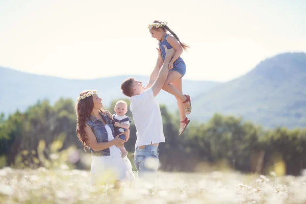 Familia feliz en un campo de margaritas florecientes — Foto de Stock