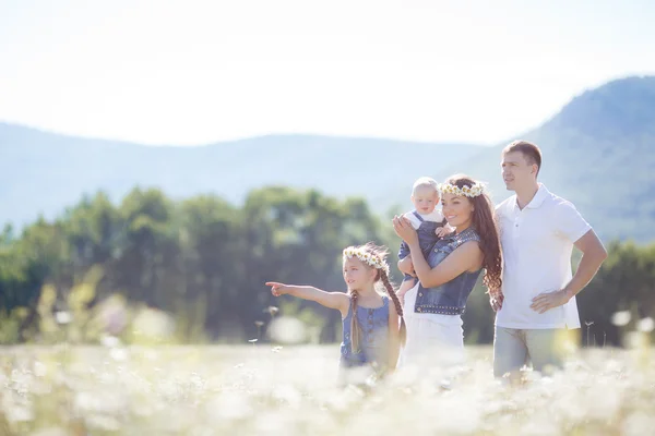 Familia feliz en un campo de margaritas florecientes — Foto de Stock