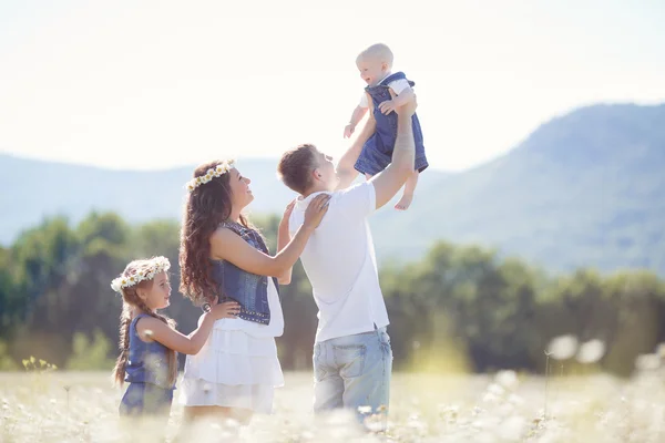 Happy family on a field of blooming daisies — Stock Photo, Image