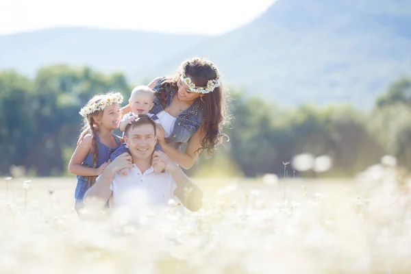 Família feliz em um campo de margaridas florescendo — Fotografia de Stock