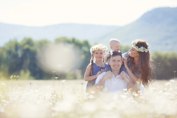 Familia feliz en un campo de margaritas florecientes — Foto de Stock