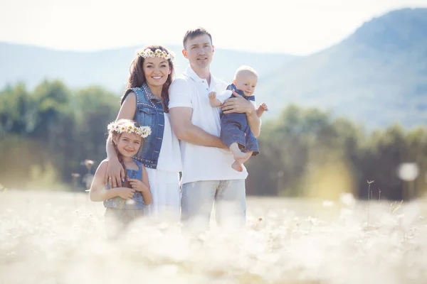 Glückliche Familie auf einem Feld blühender Gänseblümchen — Stockfoto