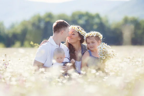 Szczęśliwa rodzina na polu kwitnący stokrotki — Zdjęcie stockowe