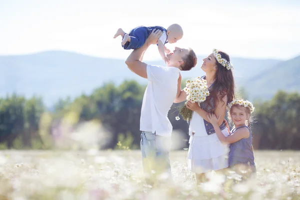 Glückliche Familie auf einem Feld blühender Gänseblümchen — Stockfoto