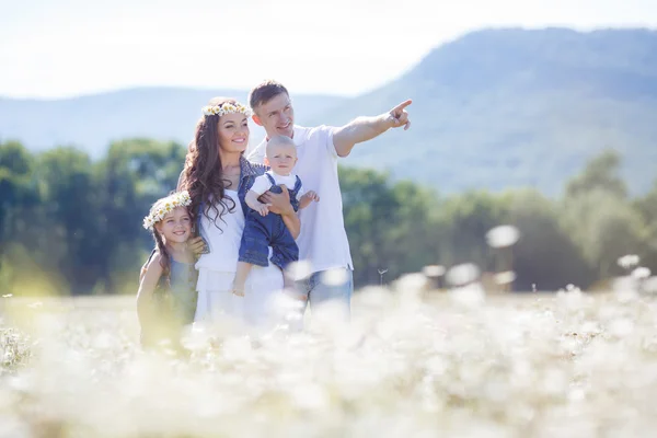 Lycklig familj på ett fält av blommande tusenskönor — Stockfoto