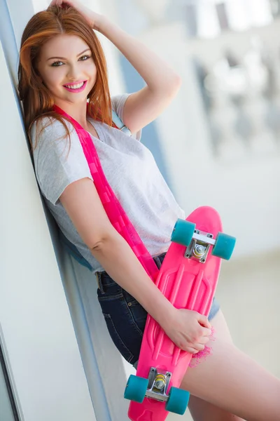 Beautiful red-haired woman posing with a skateboard — Stock Photo, Image