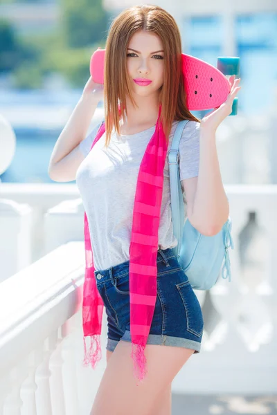 Beautiful red-haired woman posing with a skateboard — Stock Photo, Image