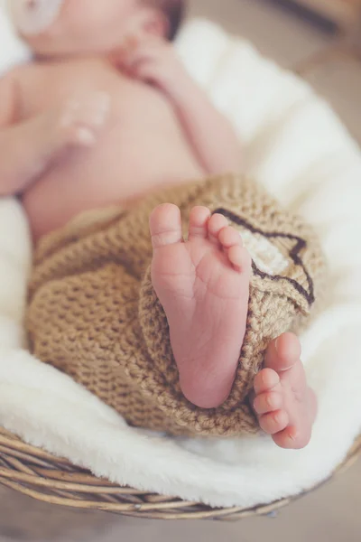 Zbliżenie z nogi noworodka, spanie w wiklinowym koszu — Zdjęcie stockowe