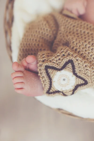 Primer plano de las piernas de un recién nacido, durmiendo en una canasta de mimbre —  Fotos de Stock