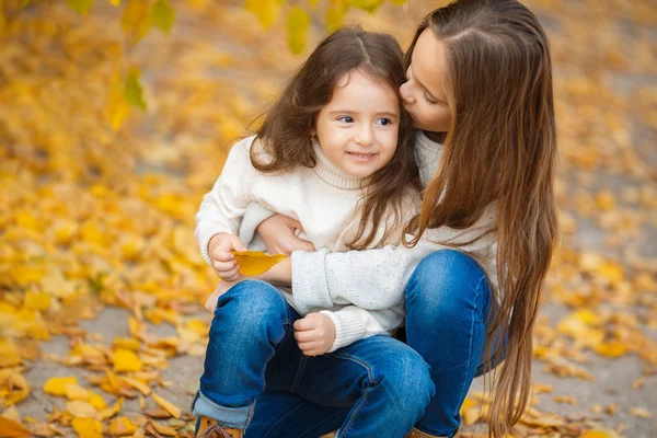 Cute girl with her younger sister in the autumn Park — Stock Photo, Image