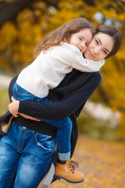 Молодая красивая мать со своей маленькой дочерью в осеннем парке — стоковое фото