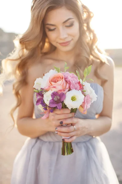 Noiva com um buquê de flores em um vestido de noiva perto do mar — Fotografia de Stock