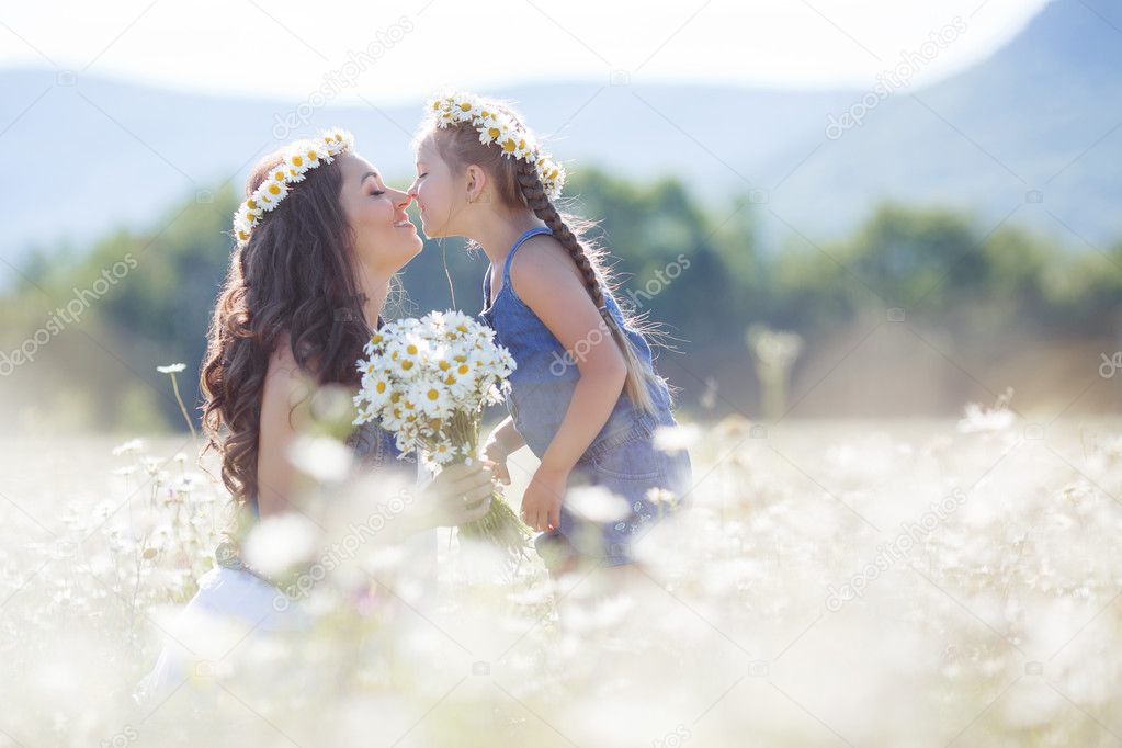 Mother and daughter in summer field of blooming daisies