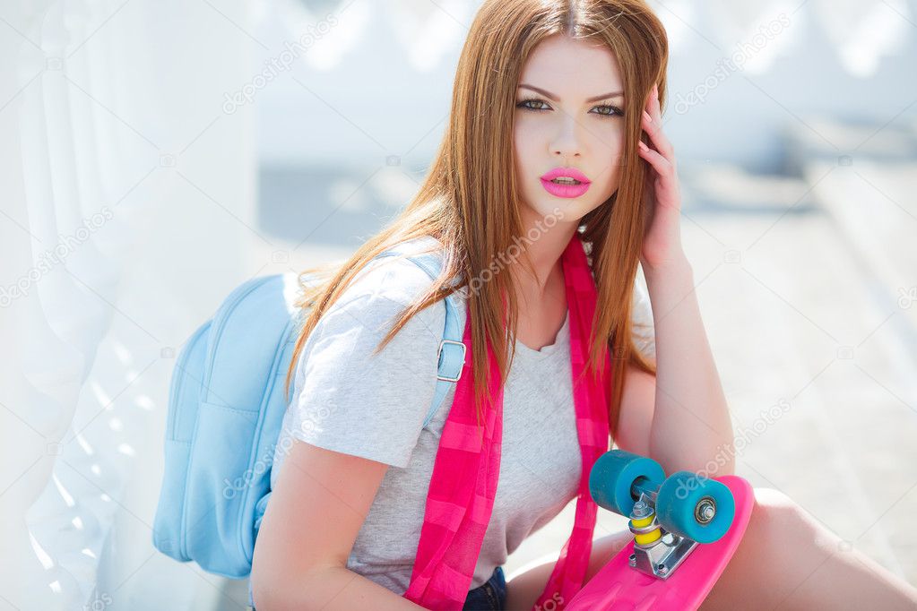 Beautiful red-haired woman posing with a skateboard