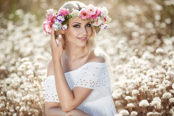 Vacker kvinna med en krans av blommor i sommar fält — Stockfoto