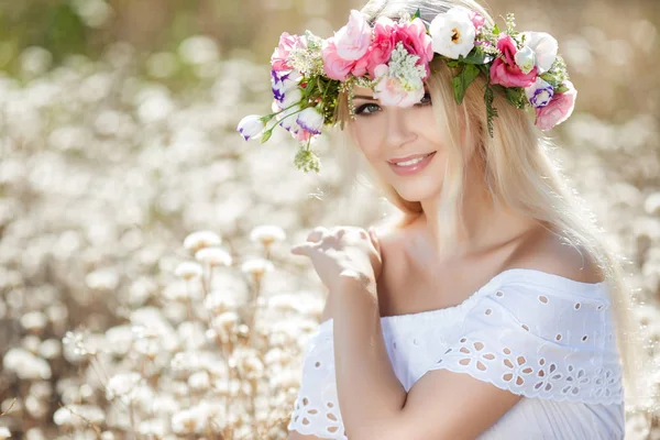 Hermosa mujer con una corona de flores en el campo de verano — Foto de Stock