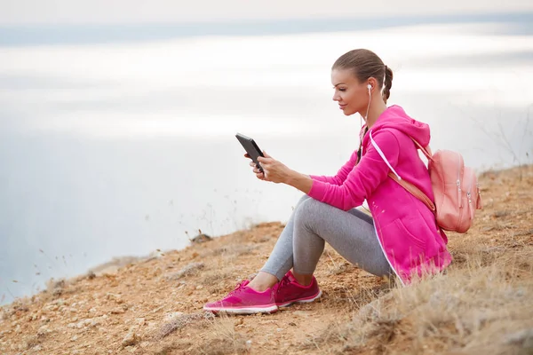 Mulher em uma praia rochosa com um tablet na primavera — Fotografia de Stock