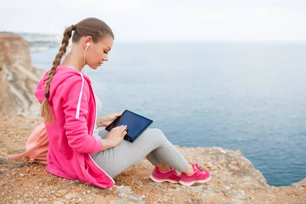 Woman on a rocky beach with a tablet in the spring — Stock Photo, Image