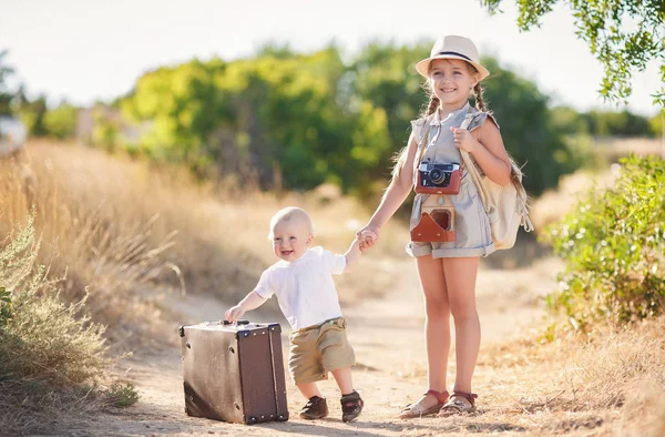 Kleiner Bruder mit einer älteren Schwester und einem großen Koffer — Stockfoto