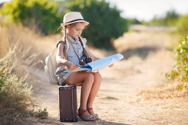 Pequeno viajante estuda o mapa enquanto se senta na velha mala — Fotografia de Stock