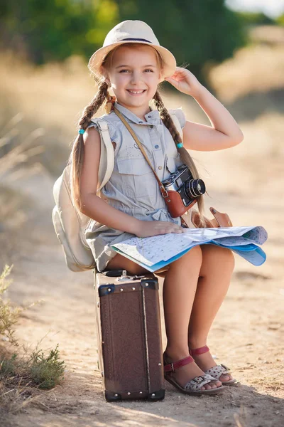 Kleiner Reisender studiert die Karte, während er auf dem alten Koffer sitzt — Stockfoto