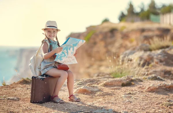 Lilla traveler studerar kartan medan du sitter på den gamla resväskan — Stockfoto