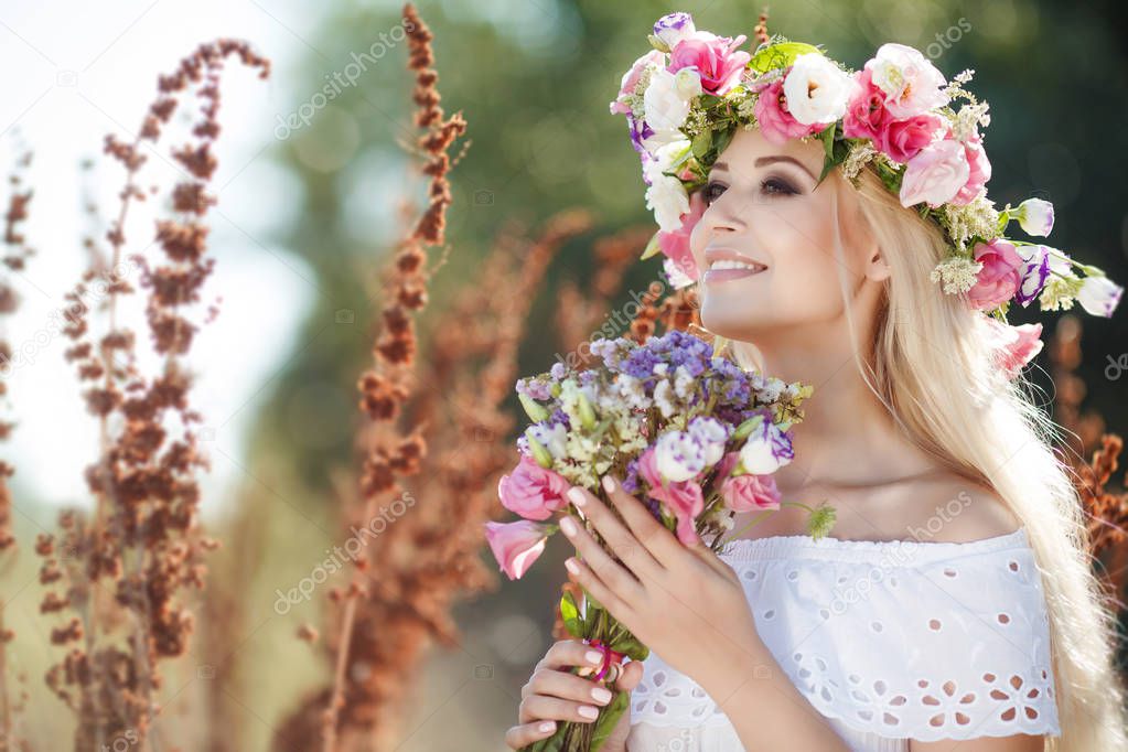  Beautiful woman with a wreath of flowers in summer field