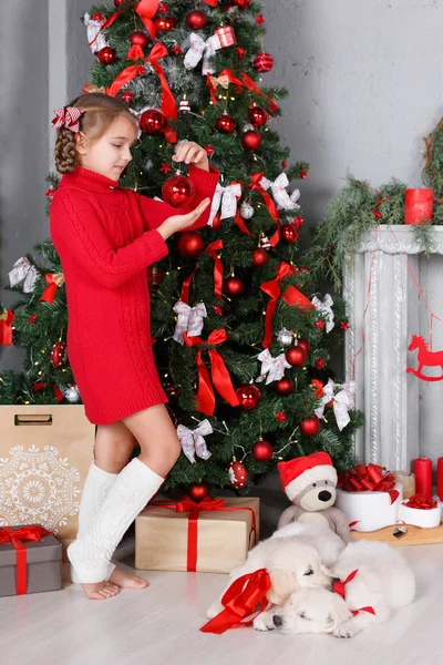 Chica feliz con dos cachorros Golden Retriever sobre un fondo de árbol de Navidad —  Fotos de Stock