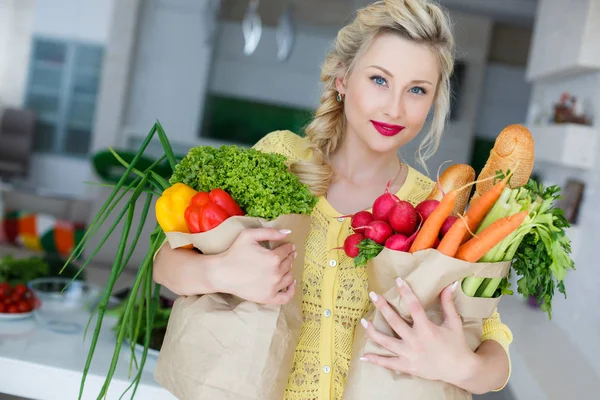 Gelukkig jonge huisvrouw met tassen vol met groenten — Stockfoto