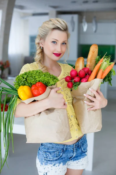Gelukkig jonge huisvrouw met tassen vol met groenten — Stockfoto